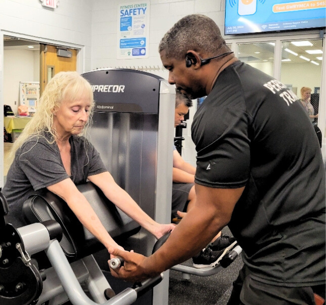 Shawn Cofield Instructing a Client How to Use a Weight Machine