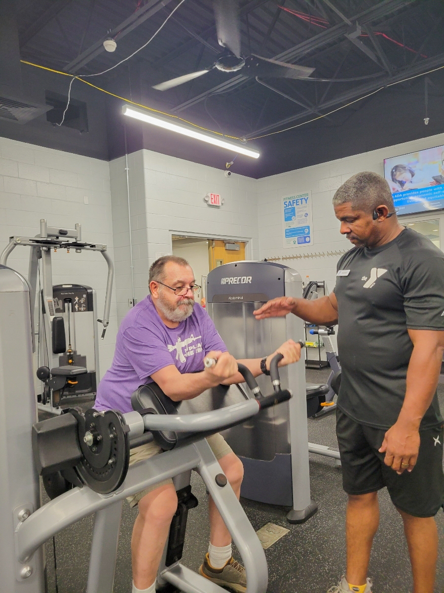 Shawn Cofield training a man to use a weight machine